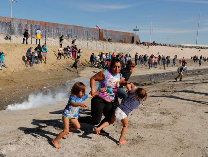 A migrant family, part of a caravan of thousands traveling from Central America en route to the United States, run away from tear gas in front of the border wall between the U.S and Mexico in Tijuana
